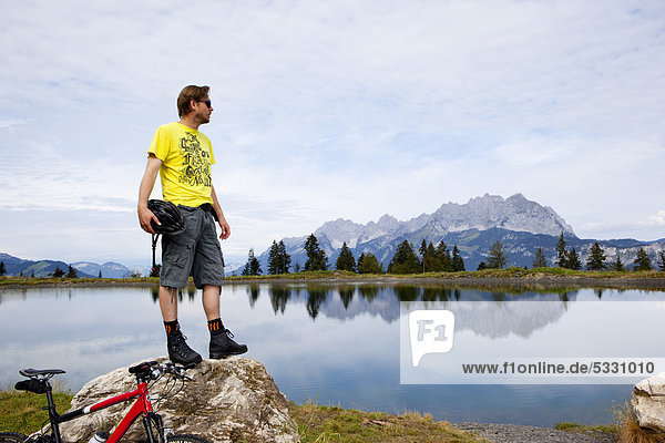 Man with mountainbike on a rock looking around