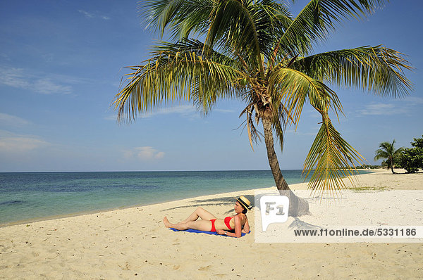 Touristin unter einer Palme am Strand  Playa AncÛn  bei Trinidad  Kuba  Karibik