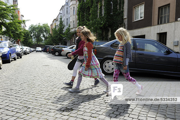 Three girls crossing a residential street in the centre of Dusseldorf  North Rhine-Westphalia  Germany  Europe