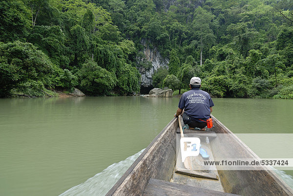 Laotian man with a simple long boat at the entrance of the 7.5 km long cave of Tham Kong Lor  in the dense tropical rain forest  Khammouane  Laos  Southeast Asia