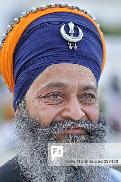 Sikh with Khanda emblem  symbol of Sikhism on turban  portrait  Harmandir Sahib or Golden Temple  Amritsar  Punjab  North India  India  Asia