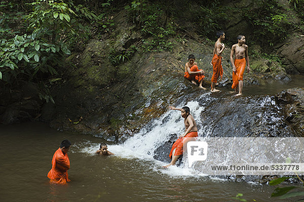 Buddhist monks having a bath in a waterfall in the jungle  Khao Phanom Bencha National Park  Krabi  Thailand  Asia