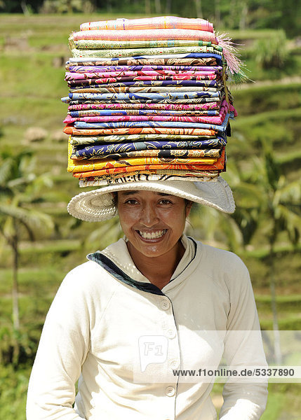 Indonesische Frau trägt einen Stapel Seidentücher auf dem Kopf  Tegalalang  Bali  Indonesien  Südostasien