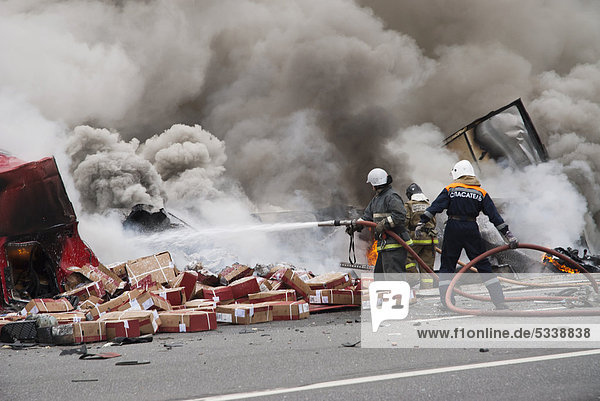 Firemen extinguishing a fire due to lorry collision on the Federal road between Moscow and Saint Petersburg  Novgorod region  Russia