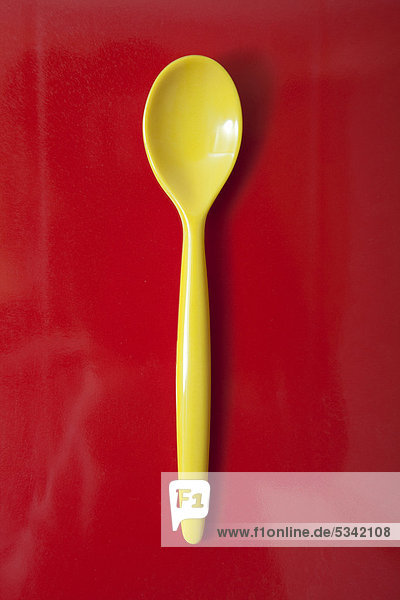 Yellow plastic spoon  egg spoon  on red