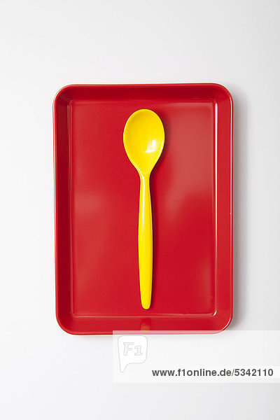 Yellow plastic spoon  egg spoon  on a tray