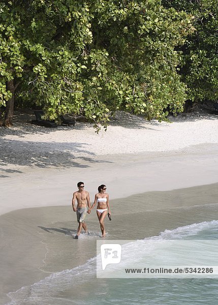 Couple walking on Emerald Bay at Pangkor Laut Resort in Malaysia