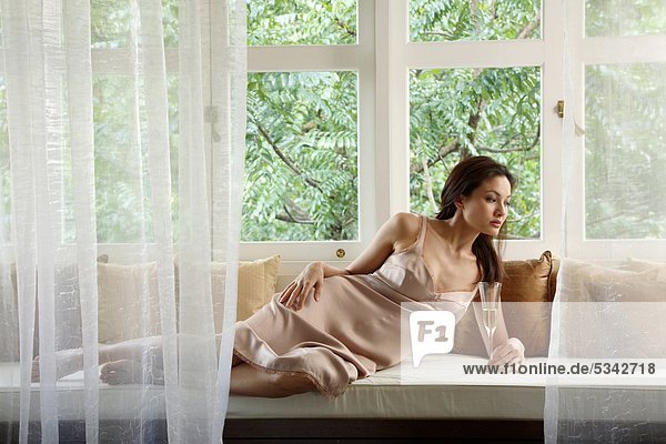 Woman lying on Sofa mit Champagnerglas