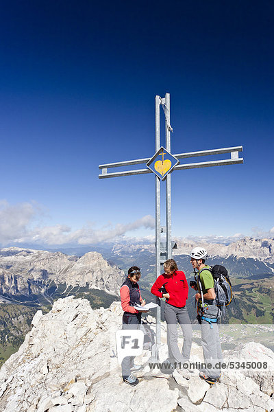 Bergsteiger am Gipfelkreuz  Klettersteig Boeseekofel  Dolomiten  hinten die Fanesgruppe und Heiligkreuzkofelgruppe  Südtirol  Italien  Europa