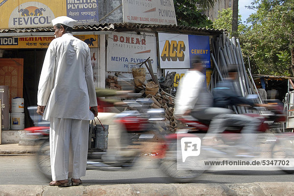 Dabba wallah or food deliverer with Dabbas or food containers crossing a street in Mumbai  India  Asia