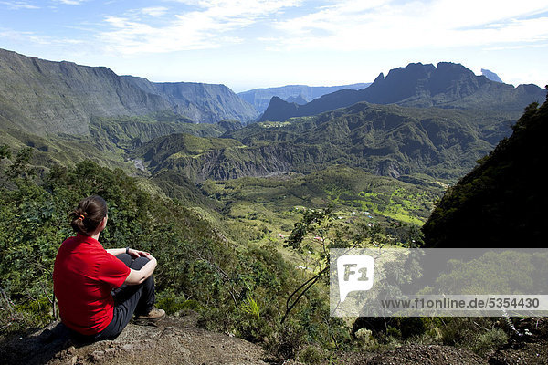 Hiker overlooking the remote and hard to reach mountain villages of La Nouvelle and Marla  Cirque de Mafate caldera  La Reunion island  Indian Ocean