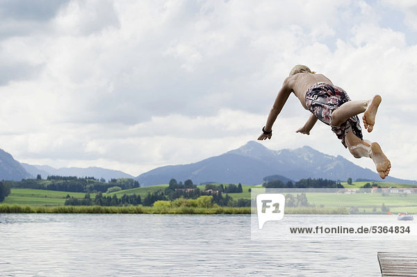 Boy jumping into Lake Hopfensee near Fuessen  Allgaeu  Bavaria  Germany  Europe