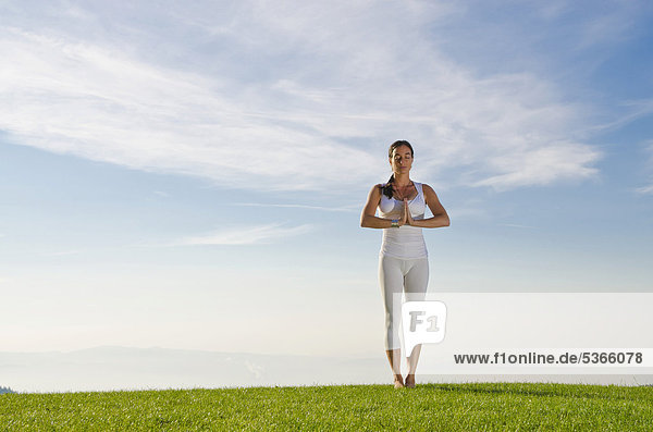 Junge Frau praktiziert Hatha-Yoga im Freien  zeigt die Stellung tadasana  pranamasana  Grußhaltung  Gebetshaltung  Nove Mesto  Okres Teplice  Tschechische Republik  Europa