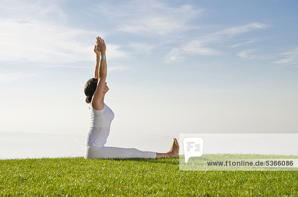 Junge Frau praktiziert Hatha-Yoga im Freien  zeigt die Stellung dandasana  Stabstellung  aufrechter Sitz  Nove Mesto  Okres Teplice  Tschechische Republik  Europa