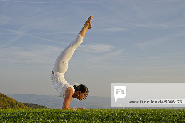 Junge Frau praktiziert Hatha-Yoga im Freien,  zeigt die Stellung vrischikasana,  Skorpion,  Nove Mesto,  Okres Teplice,  Tschechische Republik,  Europa