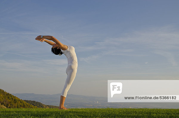 Junge Frau praktiziert Hatha-Yoga im Freien  zeigt die Stellung surya namaskar 3  Sonnengruß 3  Nove Mesto  Okres Teplice  Tschechische Republik  Europa