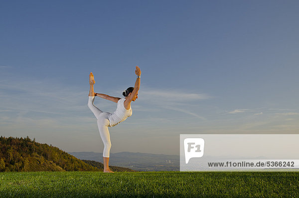 Junge Frau praktiziert Hatha-Yoga im Freien  zeigt die Stellung saral natarajasana  Tänzer  Nove Mesto  Okres Teplice  Tschechische Republik  Europa