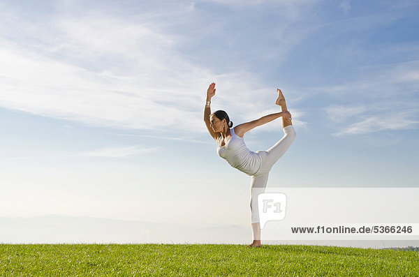 Junge Frau praktiziert Hatha-Yoga im Freien  zeigt die Stellung anjaneyasana  Spagat im Stehen  Nove Mesto  Okres Teplice  Tschechische Republik  Europa