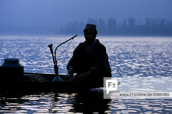Fisherman having a rest and smoking waterpipe on Dal Lake  Srinagar  Jammu and Kashmir  India  Asia