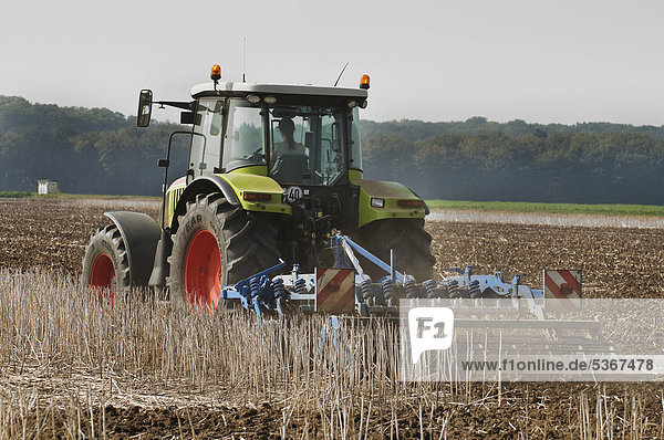 Traktor mit Grubber auf abgeerntetem Acker  Boden wird gelockert  Pflanzenreste werden in die Krume eingearbeitet  ÖffentlicherGrund