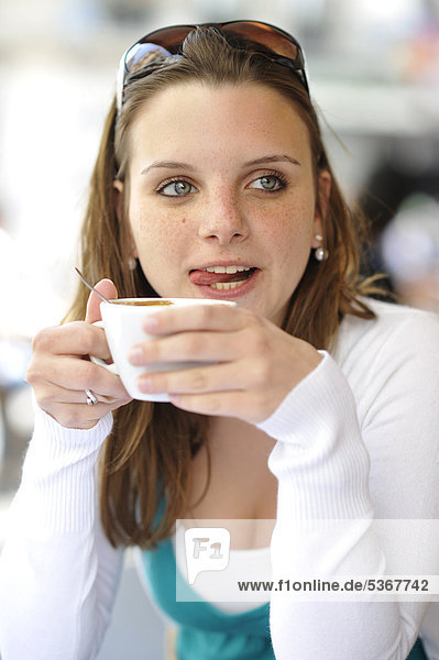 Junge Frau trinkt Kaffee  hält Kaffeetasse  in CafÈ  Paris  Frankreich  Europa mund