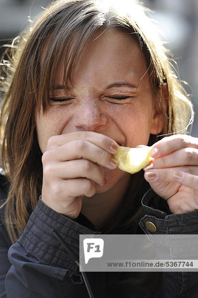 Junge Frau beißt in Zitrone und lacht  Paris  Frankreich  Europa