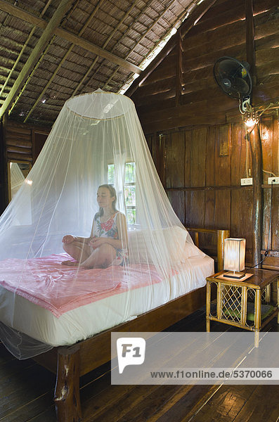 Frau meditiert unter Moskitonetz im Bungalow  Lom Lae Resort  Insel Ko Yao Noi  Phang Nga  Thailand  Südostasien  Asien