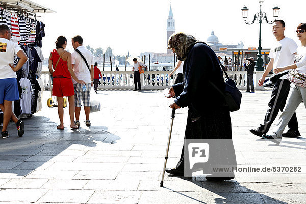 Lady begger walking amongst tourists Venice Italy Europe