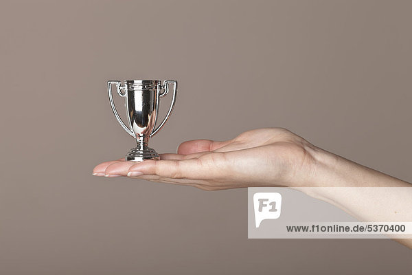 Kleiner Pokal  von weiblicher Hand präsentiert