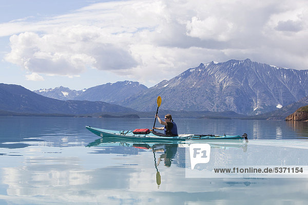 Young woman in a sea kayak  paddling  sea kayaking  mountains behind  Tagish Highland  Mount Fetterly  Atlin Lake  British Columbia  Canada  America