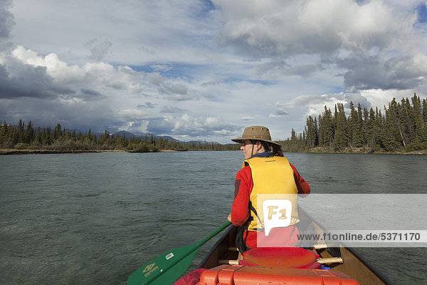 Young woman paddling a canoe  canoeing Takhini River  Yukon Territory  Canada