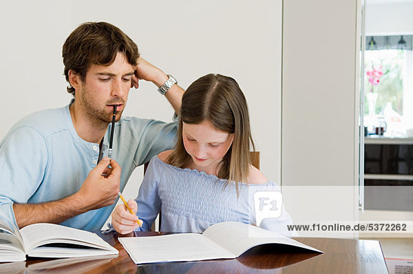 Junger Mann Tochter bei Hausaufgaben helfen