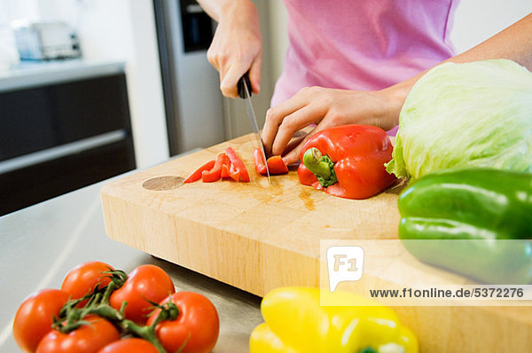 Junge Frau beim Schneiden von Gemüse in der Küche