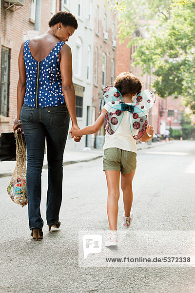 Mutter und Tochter gehen die Straße entlang  Rückansicht