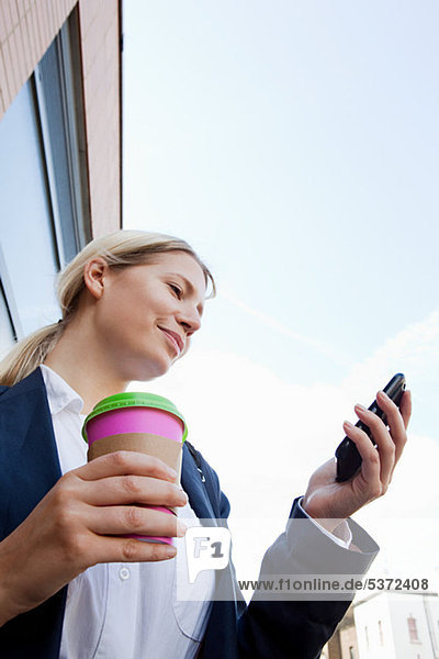 Geschäftsfrau mit Kaffee und Smartphone