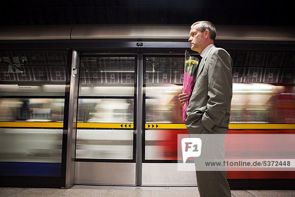 Geschäftsmann auf U-Bahn-Plattform mit Blumen