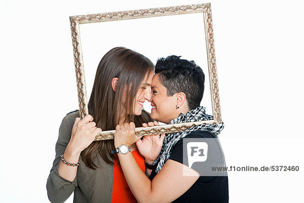 Lesbian couple holding picture frame against white background