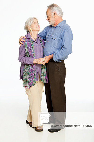 Senior Couple embracing against white background
