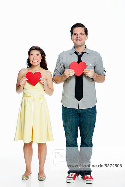 Young Couple holding Herzen Formen against white background
