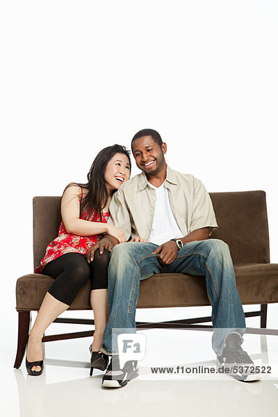 Gemischte Abstammung couple on Sofa against white background