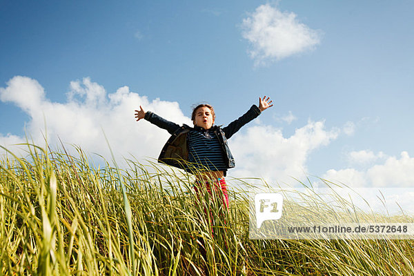 Girl holding arms out in long grass