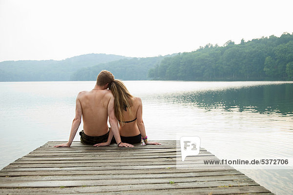 Paar auf dem Pier sitzend mit Blick auf den See