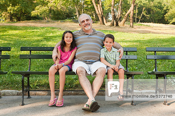 Grandfather sitting with grandchildren in park  portrait