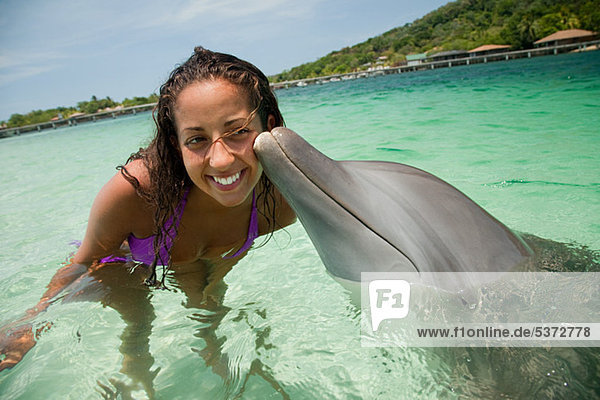 Junge Frau lächelt mit Delphin im Meer