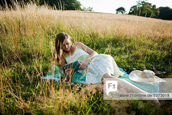 Junge Frau liegen auf Seite in einem Feld auf ein Handgerät
