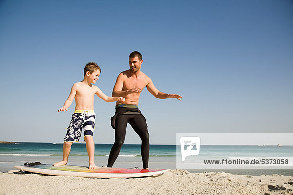 Father teaching son how to surf