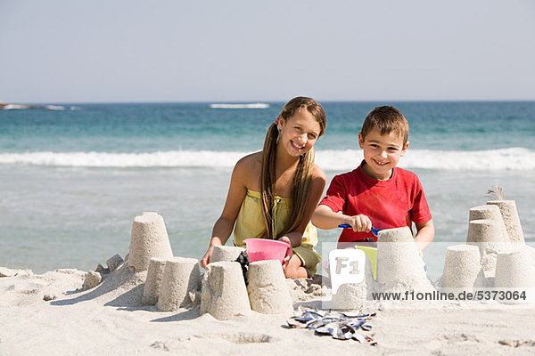 Mädchen und Junge machen Sandburgen am Strand