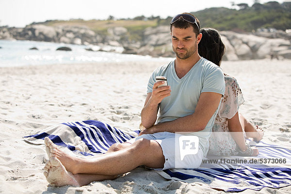 Young couple relaxing back to back on a beach