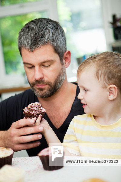 Young boy passing cupcake to his father