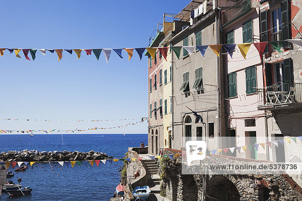 Italien  Ligurien  Riomaggiore  Cinque Terre  Blick auf Dorfgebäude mit Fahnentuch und Meer im Hintergrund